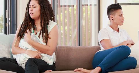 Concerned Friend Supporting Woman with Stomach Pain at Home