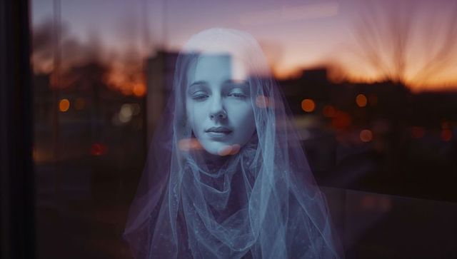 Ethereal teenage girl behind dotted veil at sunset