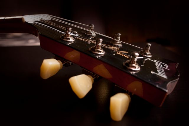 This image captures a detailed close-up view of a guitar headstock featuring the tuning pegs and strings. It's ideal for use in media related to music, musical instruments, or guitar manufacturing. Perfect for blogs, tutorials, or advertisements involving guitar maintenance or musical education.
