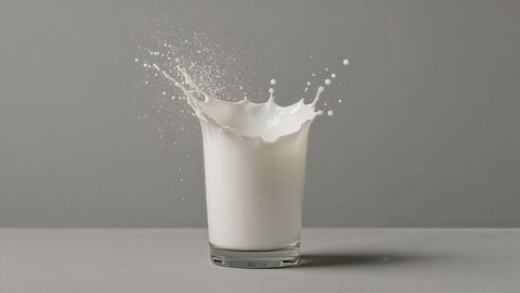 Dynamic Milk Splash in Clear Glass on Grey Background