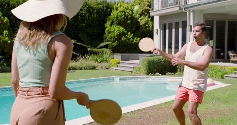 Friends Playing Paddle Ball in Scenic Backyard Garden