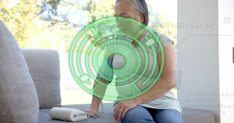 Asian senior checking blood pressure at home with digital monitor and green hud overlay