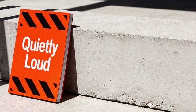 Quietly loud orange caution sign leaning on concrete ledge with bold black stripes