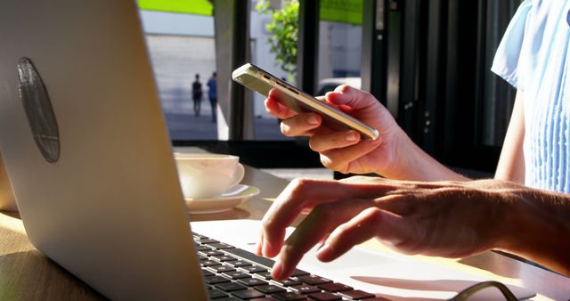 Close-Up of Hands Using Smartphone and Laptop in Sunlit Cafe - Download Free Stock Images Pikwizard.com