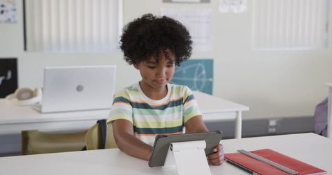 Elementary Student Using Tablet on Stand at Classroom Desk for Digital Learning