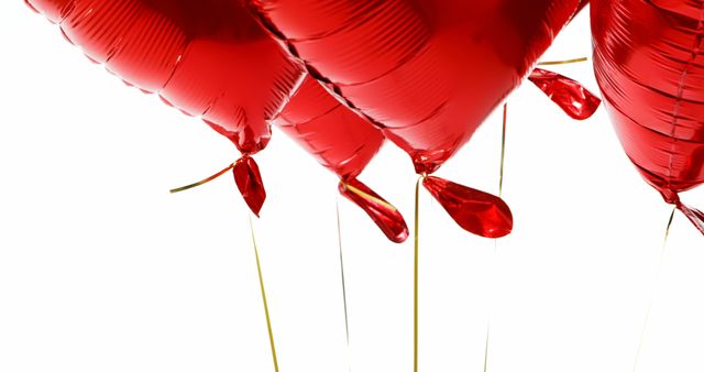Red heart-shaped helium balloons hovering with strings against a white backdrop. Ideal for Valentine's Day promotions, romantic event decorations, celebration invitations, and love-themed marketing content.