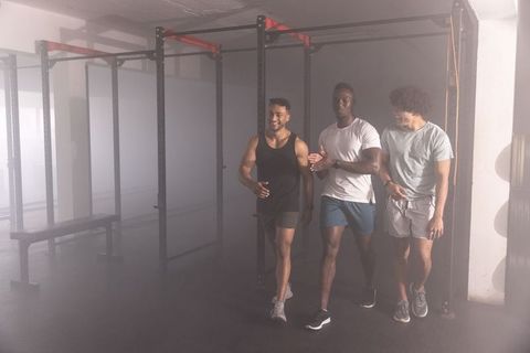 Diverse male friends walking together in industrial gym rig sharing workout camaraderie