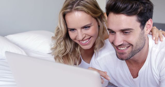 Happy couple smiling and using laptop together on bed - Download Free Stock Images Pikwizard.com