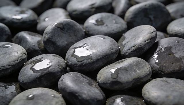 Wet smooth river stones glistening with water droplets close-up texture for zen design