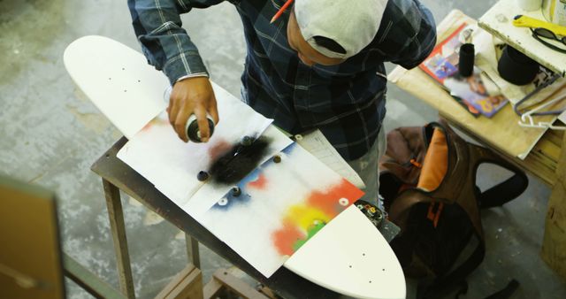 Young Man Customizing Skateboard Deck with Spray Paint - Download Free Stock Images Pikwizard.com