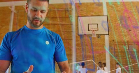 Male basketball coach supervising school gym class, checking hands and leading youth drills