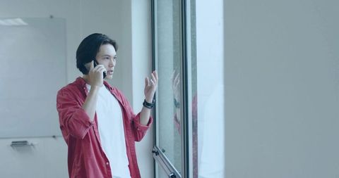 Young Professional Speaking on Phone by Office Window