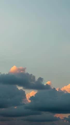 Vertical sunset sky showing cumulus clouds drifting over horizon