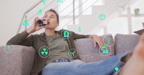 Woman Enjoying Beverage on Sofa with Eco-Friendly Icons Concept