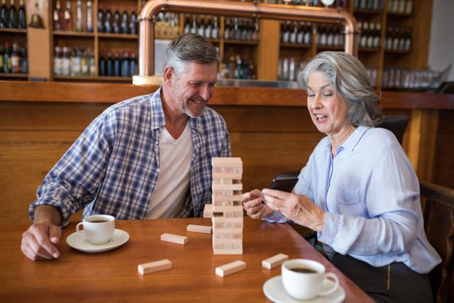 Happy senior friends playing jenga game on table in bar