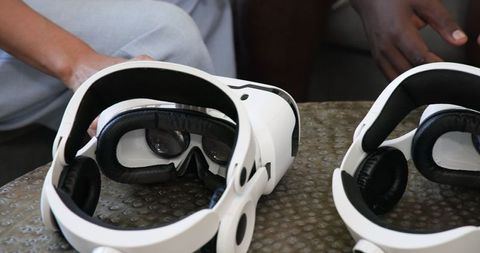 Diverse friends exploring with white vr headsets on coffee table