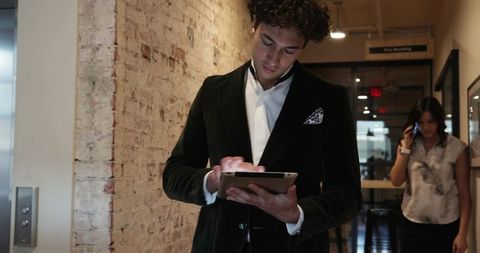 Young Businessman Using Tablet in Modern Office Corridor