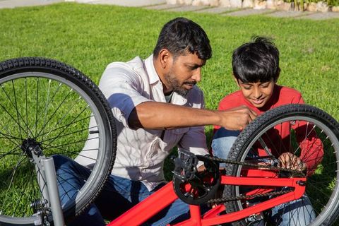 Father and Son Repairing Bicycle on Sunny Day in Backyard