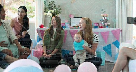 Joyful pastel baby shower with friends holding newborn, cupcakes, balloons, gifts, recording