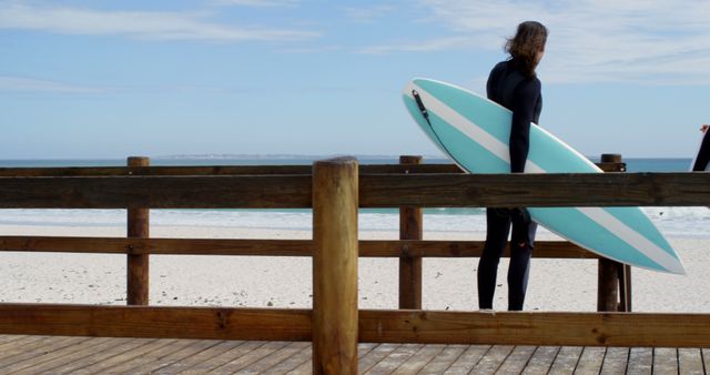 Surfer with Surfboard on Wooden Deck Facing Ocean - Download Free Stock Images Pikwizard.com