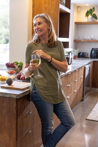 Woman Enjoying Wine in Modern Kitchen with Fresh Ingredients