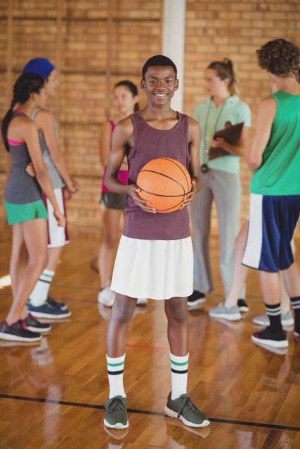 High school boy standing with basketball in the court - Download Free Stock Photos Pikwizard.com