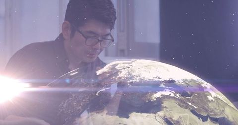 Mature asian man engaging with virtual earth globe in futuristic office
