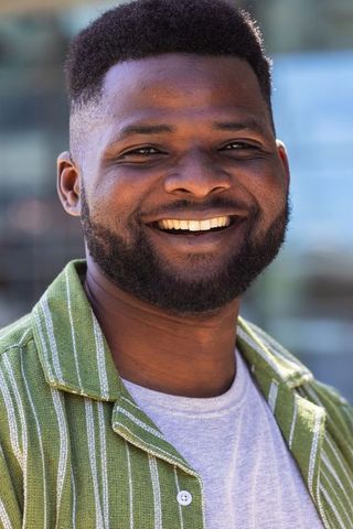 African american man smiling outdoors in green striped shirt urban headshot sunlit daylight