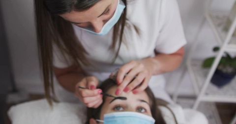 Professional Esthetician Applying Eyebrow Treatment in Spa