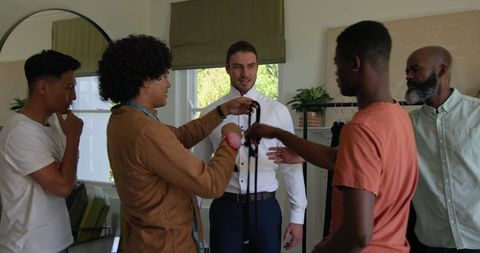 Groomsmen assisting groom with bow tie before wedding ceremony