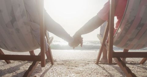 Senior Couple Holding Hands Relaxing on Beach at Sunset