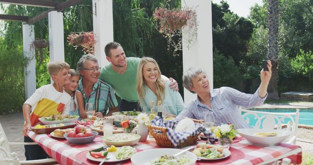 Large multi-generational family gathered around a table by the pool, sharing lunch and taking a selfie. Ideal for use in promotions of family gatherings, summer events, or food and beverage advertisements. Perfect for illustrating themes of togetherness, joy, and outdoor activities.