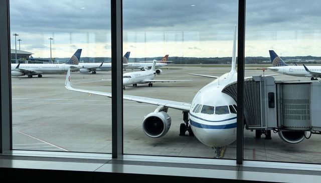 Terminal view showing narrow-body jet parking at gate with jet bridge and apron activity
