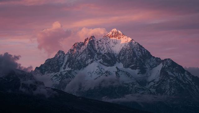 Majestic Snowy Mountain Peak at Dawn with Glowing Sky
