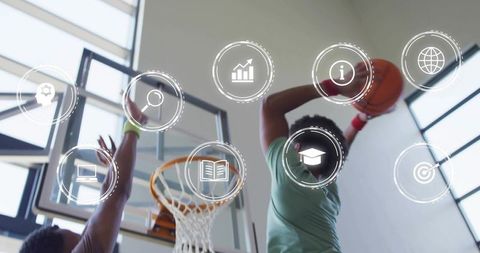 Young athlete dunking basketball, defender contesting at hoop with digital icons overlay