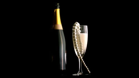 Champagne Bottle with Flute and Pearls on Black Background