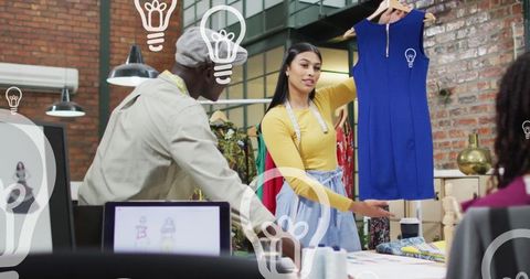 Designers collaborating in modern fashion studio on blue dress creation