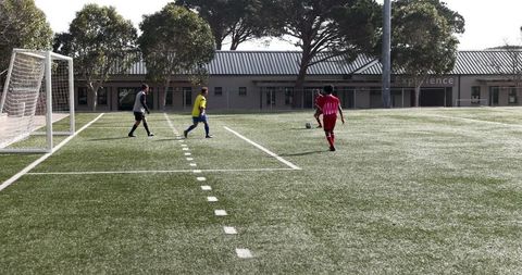 Soccer players practicing on sunny day at outdoor sports field