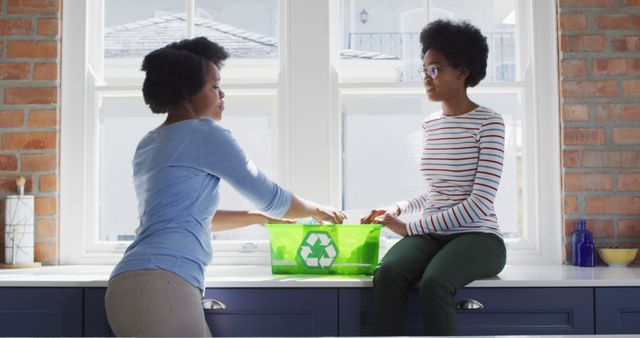 Happy african american mother and daughter recycling together in kitchen. domestic life and quality family time together at home.