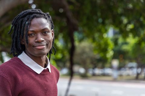 Confident african american young man with dreadlocks wearing maroon sweater urban portrait