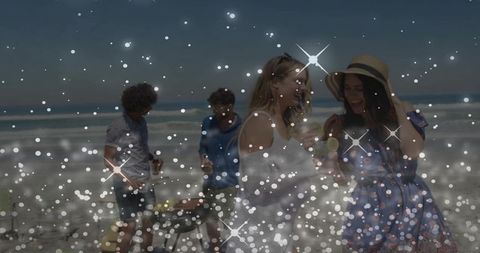 Friends enjoying beach barbecue with lemon drinks and sparkle bokeh overlay