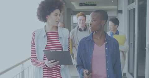 Diverse young coworkers walking, collaborating in bright modern office corridor, teamwork