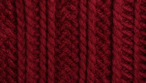 Close-up burgundy cable-knit texture showing chunky yarn plies, ribbing and soft halo
