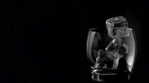 Ice Cubes in Motion with Elegant Glass on Black Background