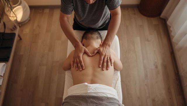 Therapist applying relaxing back massage on male client in minimalist spa wellness room