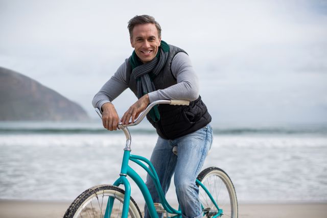 Portrait of smiling mature man riding bicycle on the beach