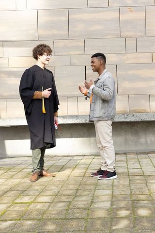 Diverse male friends celebrating college graduation in campus courtyard