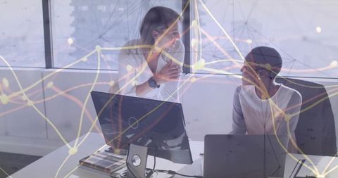 Businesswomen discussing data analysis in modern office environment
