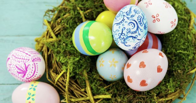 The image depicts a collection of colorful hand-painted Easter eggs resting in a nest made of green moss on a light blue background. Each egg features unique patterns and designs, showcasing intricate, creative artwork. This scene is perfect for illustrating Easter celebrations, spring festivities, holiday decorations, traditional activities, and crafting projects. It is suitable for use in articles, advertisements, and greeting cards to convey the theme of a joyful Easter holiday.