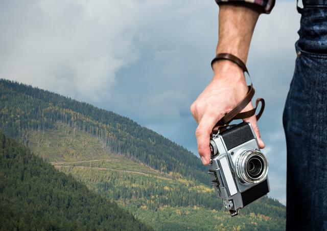 Digital composite of travel mountains. hand with camera in fron of a green mountain